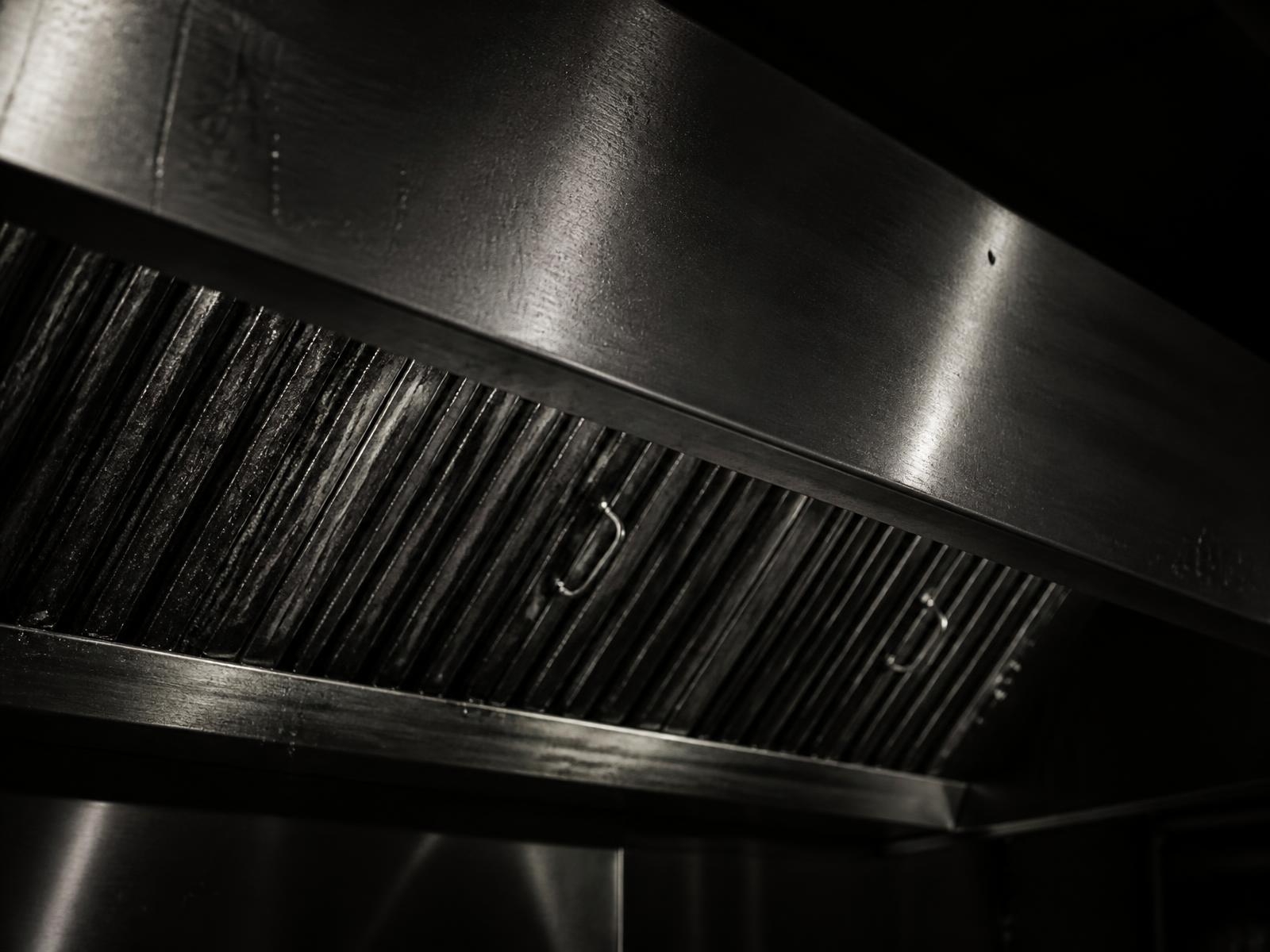 Close-up of a stainless commercial kitchen exhaust hood and grease filters